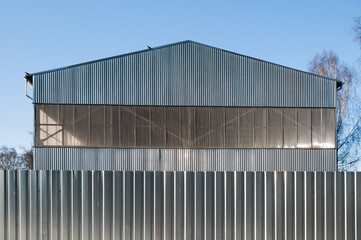 Obraz premium A close-up of a gray metal fence with a metal hangar and blue sky in the background