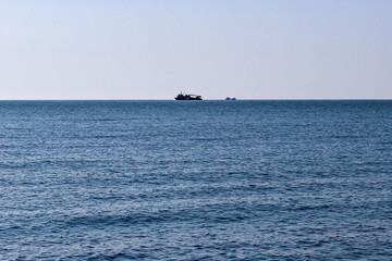 Obraz premium Fishing boats on the blue waters of the Black Sea at sunset in Abkhazia. Gentle waves and warm evening light create a calm seascape, capturing maritime life and peaceful coastal beauty.