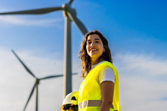 Woman engineer smiling, working at a wind farm, promoting renewable energy