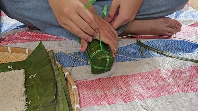 Close-up of hands skillfully wrapping Vietnamese Banh Tet, a traditional sticky rice cake for Tet holiday.