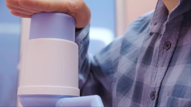 Home hydration routine woman pressing pump on bottled water convenient eco friendly drinking solution