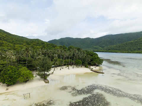 Aerial view of Bobby Beach where the white sand meets the lush green forest contrasting with the turquoise water, Karimunjawa, Central Java, Indonesia.