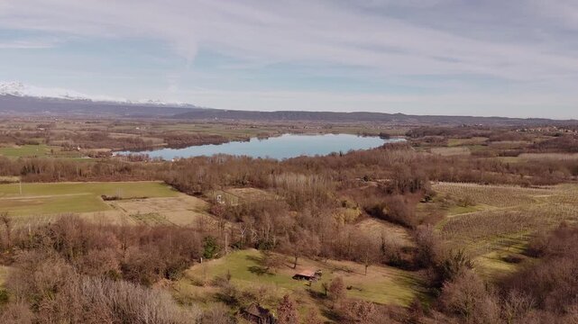 Winter aerial view of Piedmont countryside with vineyards, Candia Lake and snow-capped Alps, Northern Italy