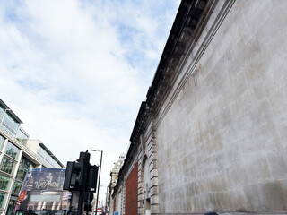 Naklejka premium London street scene with historic stone wall and Harry Potter bus banner on a storefront