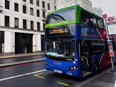 London electric double decker Golden Tours bus Blue Route at busy street stop by historic buildings