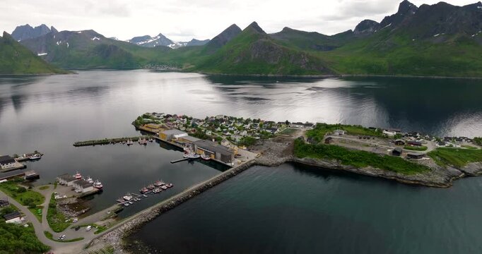 Aerial establishing of Husoy island harbor and village in Oyfjord, Senja Norway under overcast sky