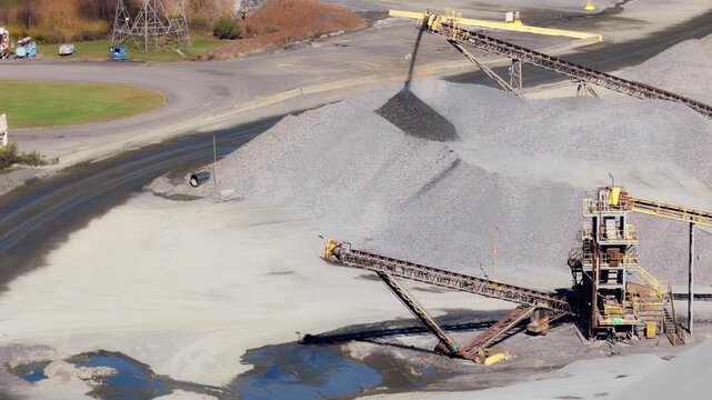 Conveyor belt pouring gravel onto stockpile at Jones Mill Quarry Arkansas USA, aerial pullback