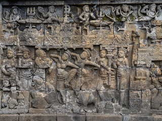 Obraz premium Closeup view of ancient stone bas-relief scene with dancing girls, Borobudur buddhist stupa, Magelang, Java, Indonesia