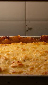 Vertical video: Showing rectangular dish cooling on counter near tiled backsplash, cheese settling