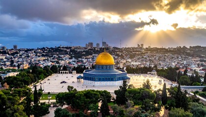 Obraz premium Sun rays peak through clouds over a city with golden dome, green trees, & pale buildings in distance