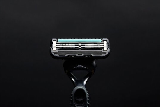 A Gillette razor blade is displayed on a dark, textured surface.