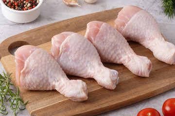Fresh chicken drumsticks and vegetables on a cutting board in a kitchen setting ready for cooking