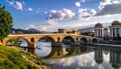 Stone bridge arches across a river, reflecting the clear sky and the domed buildings on its banks