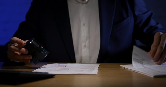 man stamping documents on the table in dark office. routine work, bureaucracy concept