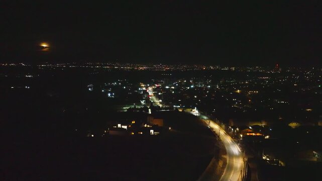 Night aerial view of city lights. Roads glow with car lights. Urban sprawl stretches into distance. Perfect for urban, travel, or nighttime projects