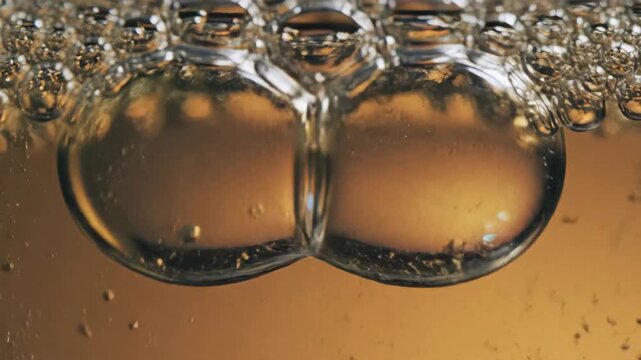 Close up macro shot of golden bubbles rising in liquid.