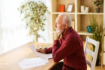 Portrait of a mature senior man a businessman working from home signing a document or an agreement,...