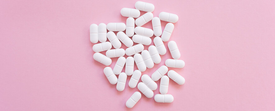 Tabletten or pillen in white package on the pink background with place for text.