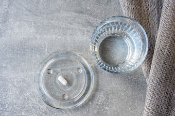 Obraz premium White pill and glass with water stay on the marble table.