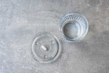 Obraz premium White pill and glass with water stay on the marble table.