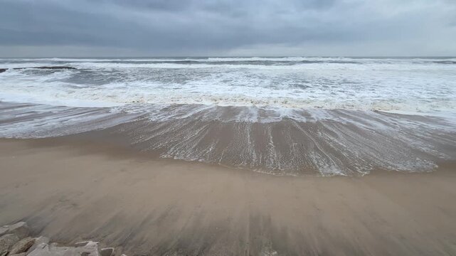 waves creeping steadily across open beach in winder Portugal