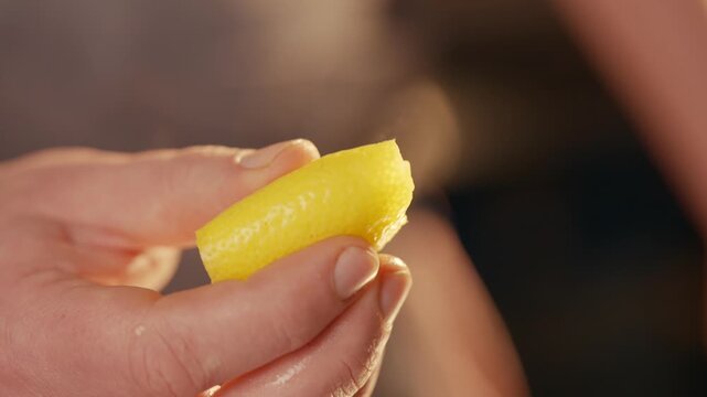 Hand holds lemon slice. Citrus juice sprays out. Steam rises from fruit. Perfect for cooking, cleaning, or refreshing visuals. Bright yellow color adds vibrancy. Ideal for food, health