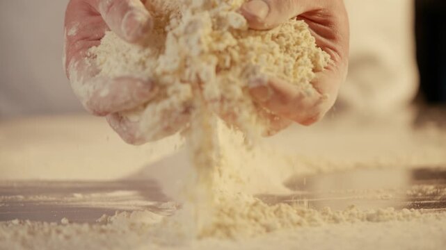 Close-up hands sift flour, dust falling slowly. Warm, golden tones highlight texture and motion. Suggests baking, cooking, or artisanal food preparation. Ideal for recipes, culinary blogs