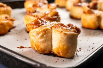 Freshly baked banana caramel puff pastry rolls on a baking sheet. Pastry. Dessert © Denis