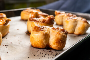 Freshly baked banana caramel puff pastry rolls on a baking sheet. Pastry. Dessert © Denis