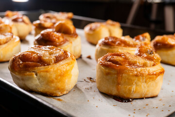 Freshly baked banana caramel puff pastry rolls on a baking sheet. Pastry. Dessert © Denis