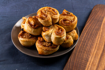 Freshly baked banana caramel puff pastry rolls on a baking sheet. Pastry. Dessert © Denis