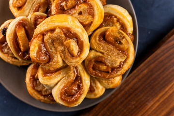 Freshly baked banana caramel puff pastry rolls on a baking sheet. Pastry. Dessert © Denis