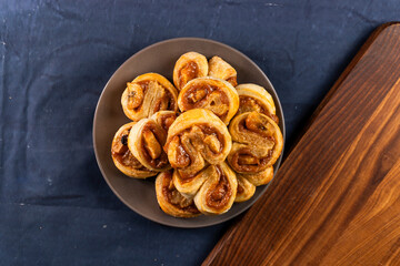 Freshly baked banana caramel puff pastry rolls on a baking sheet. Pastry. Dessert © Denis