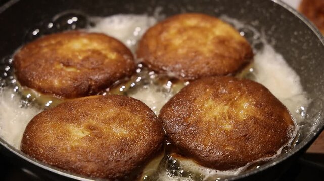 Golden brown doughnuts frying in hot oil pan for traditional Fat Thursday celebration homemade sweet pastry dessert cooking process and delicious culinary snack background.