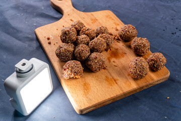 Healthy energy balls with dried apricots, cranberries, and seeds on a wooden board.