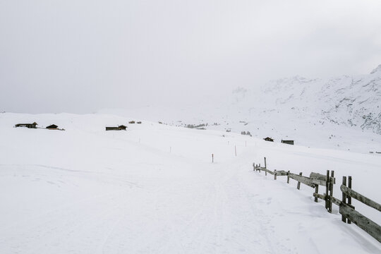 Holzh&uuml;tten auf der Seiser Alm mit Nebel und Wolken im Winter