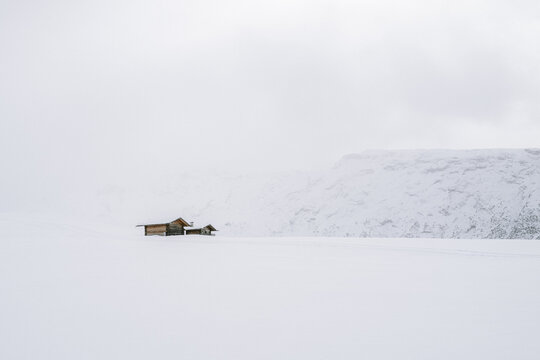 Holzh&uuml;tten auf der Seiser Alm mit Nebel und Wolken im Winter