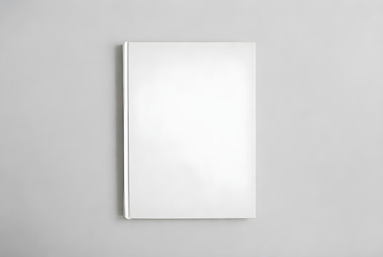 Top view of a closed white book with blank cover and spine, isolated on a solid light gray background for creative use.