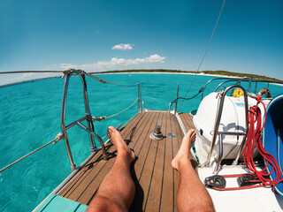 Obraz premium Legs view of male tourist enjoying boat catamaran tour during summer tour vacation - Travel, holidays and relax concept - UGC fisheye wide lens content - Main focus on feet