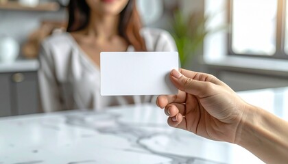 大理石のテーブルを背景にビジネスカードを差し出す女性の手元のクローズアップ
