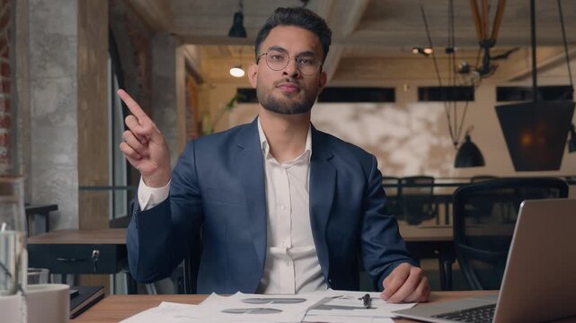 Serious Arabian business man with documents and laptop shaking finger no not gesture Indian businessman guy male in office work looking at camera showing never reject deny hand sign negative attitude