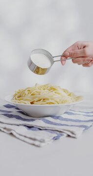 Person Putting Sauce on Pasta