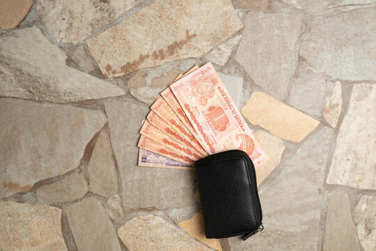 Honduran Lempira paper currency of Honduras in a fan shape with a black leather wallet on a stone tile surface