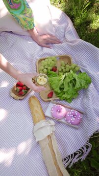 Variety of foods and snacks arranged on a picnic blanket in the park