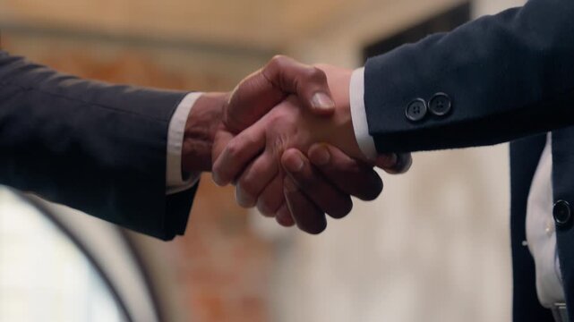 Closeup business handshaking in office deal gesture males hands shake team work multiracial greeting partnership international cooperation negotiation hire candidate two unrecognizable men businessmen