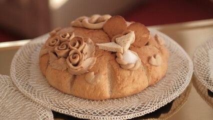 Traditional Slavic wedding bread korovai decorated with dough roses and salt on a lace doily