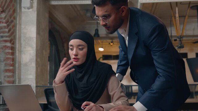 Puzzled intern Muslim businesswoman with laptop work man leader checking good job satisfied businessman support showing thumb up happy woman writing notes cooperation corporate team teamwork talking