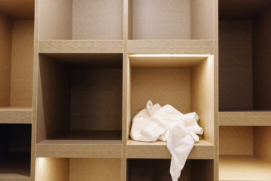 Storage shelves with cubbies and a crumpled tissue in one compartment, warm wood tones and minimalist design emphasizing simple organization and quiet interior.