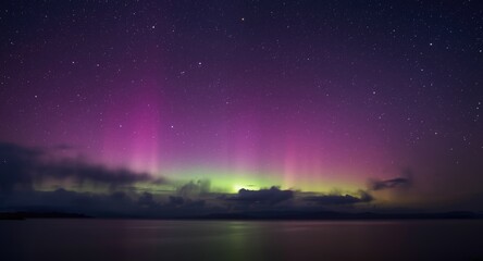 Beautiful aurora borealis with pink and purple hues over a calm starry night
