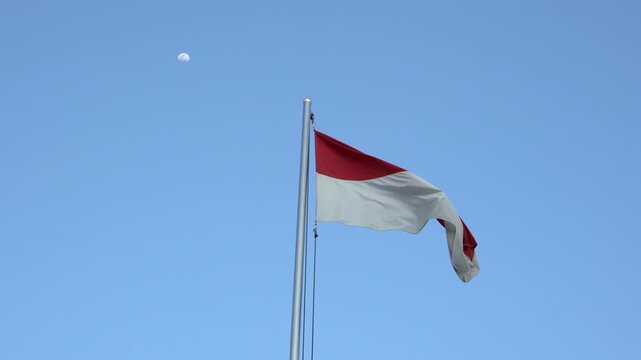 The single large red and white Indonesian flag flutters in the strong wind ahead of the 77th Independence Day of the Republic of Indonesia.	
